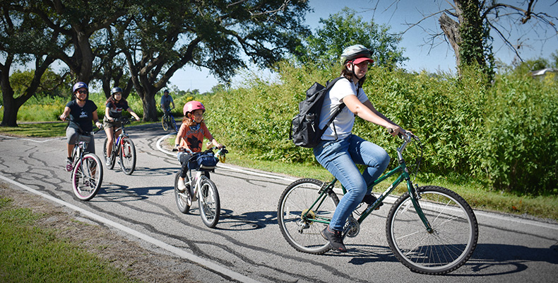 A family out riding their bikes around the San Jacinto Battlefield.