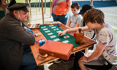 A reenactor and three boys play a card game.