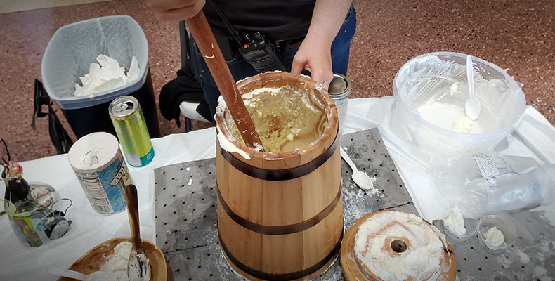 A butter churn sits on a table, surrounded by butter-making supplies.