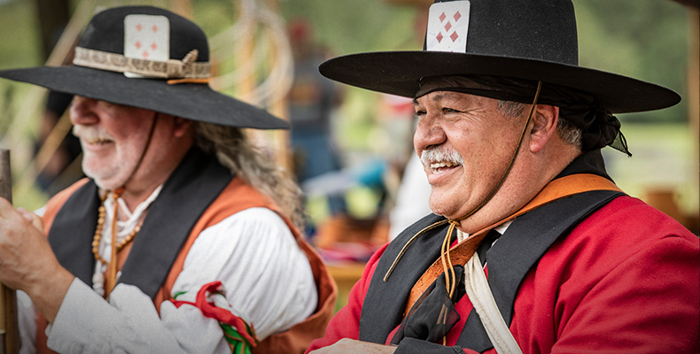 Two San Jacinto Tejano reenctors wearing cards in their hatbands.