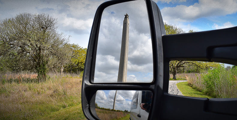 View of the San Jacinto Monument reflected in a side mirror on a touring van.