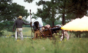 Smoke fires to the right from a cannon, with several people bending away from the explosion