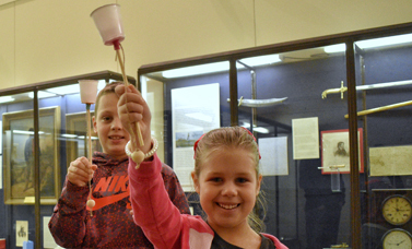 Two children smile while holding ball-and-cup toys.