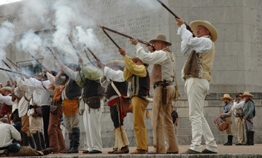 Reenactors fire a salute with long guns.