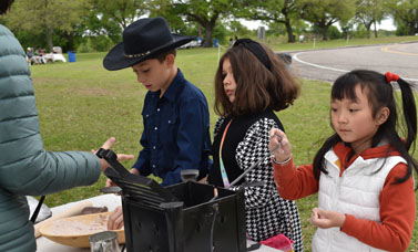 Three kids experience making camp bread.