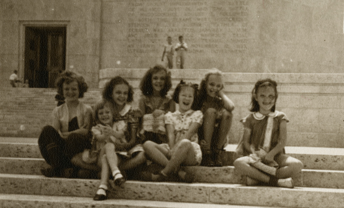 Seven little girls smile at the camera from the steps of the San Jacinto Monument.