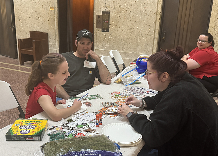 Staff interact with a child at a craft table.