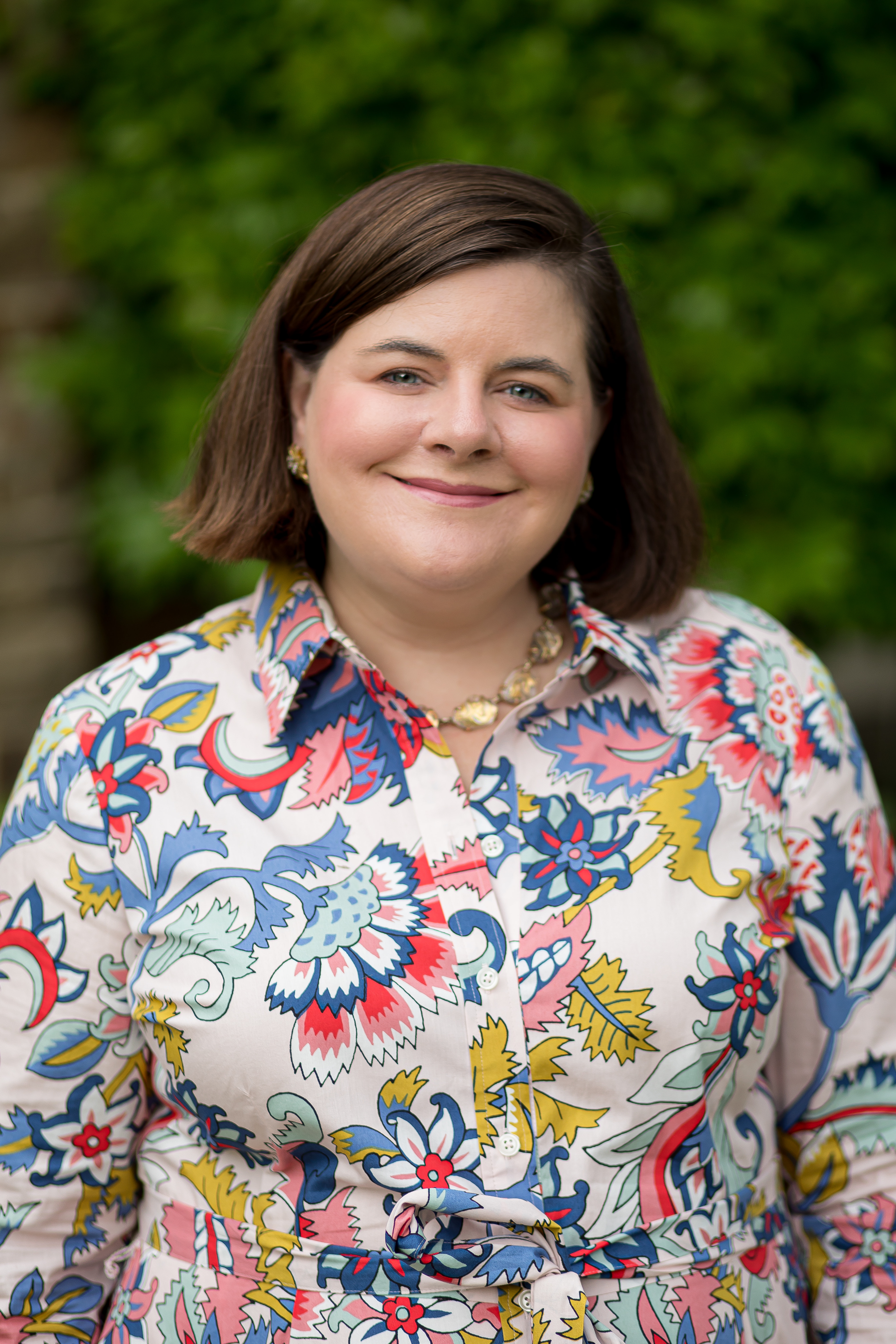 Head shot of a smiling woman with dark hair and a flowered blouse