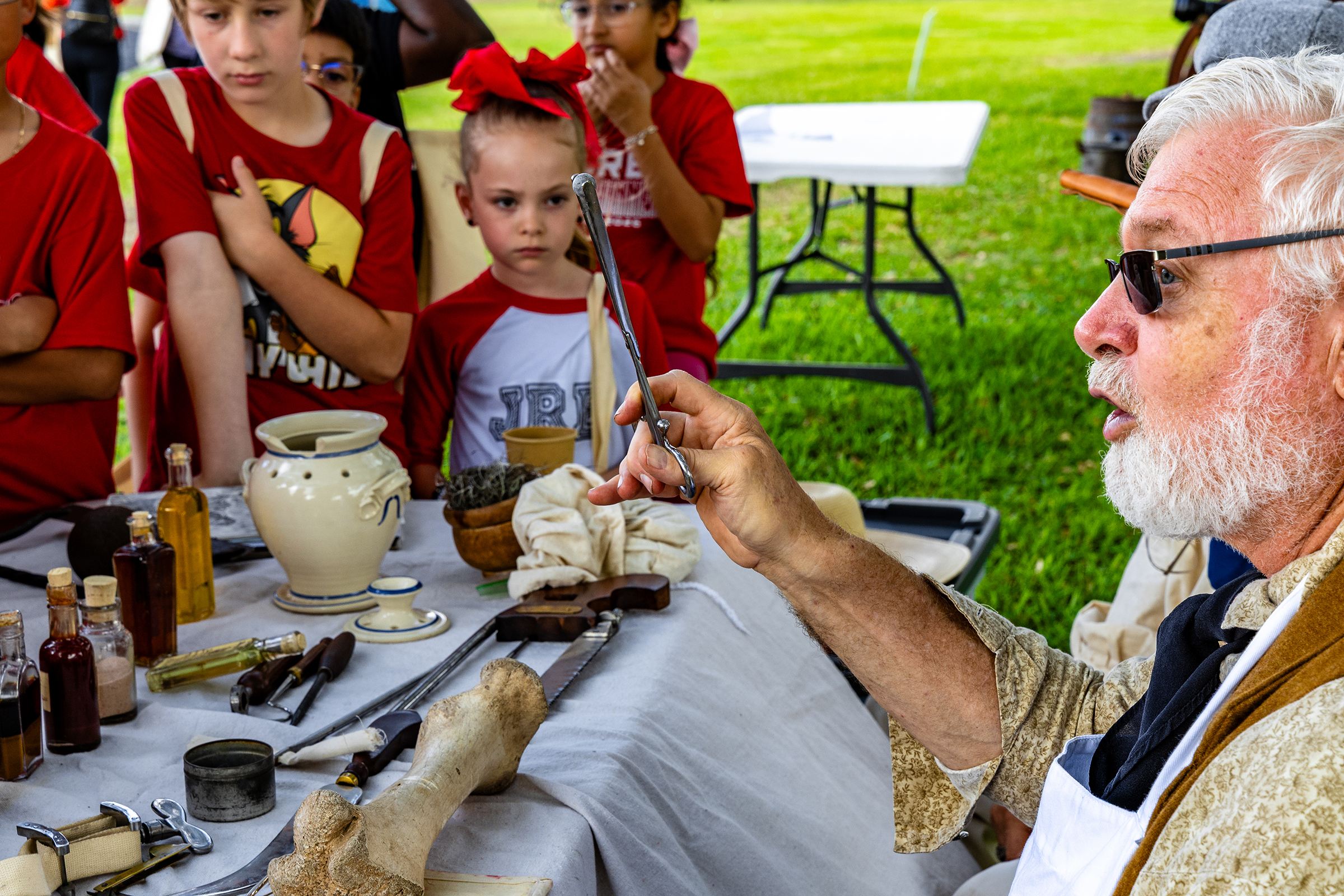 A man holds up a medical took while talking to children.