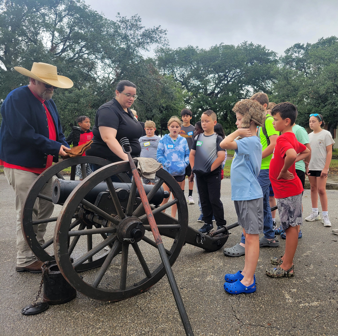 Kids gather around a cannon as educators eplain howwone is fired.