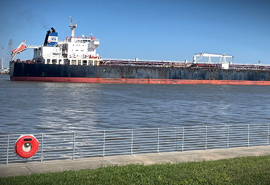A large tanker going through the Houston Ship Channel by the San Jacinto Monument